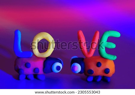 Two toy ladybugs look at each other. Next to the inscription love. Bright colored background. Decorations for Valentine's Day.