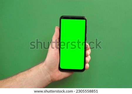 Young man hand use smartphone with green screen on green background. Gestures pack. Male hand touching, clicking, tapping swiping on black phone chromakey display. Close up Device. Modern Technology