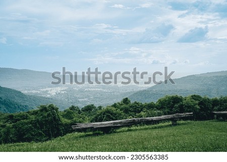 a view of nature with green grass and trees, overseeing mountains with blue sky