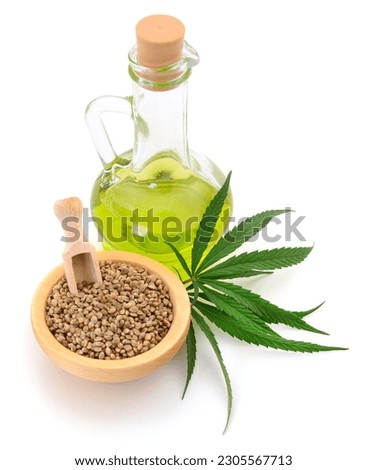 Hemp oil in glass bottle and fresh green hemp leaves on white background. Royalty-Free Stock Photo #2305567713