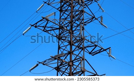 A large metal pole of a high-voltage power line against a blue sky. Production and transportation of electricity. Electricity tariffs Royalty-Free Stock Photo #2305585373