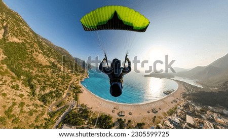 Extreme paraglider pilot flying over the beach, adventure concept. Royalty-Free Stock Photo #2305599725