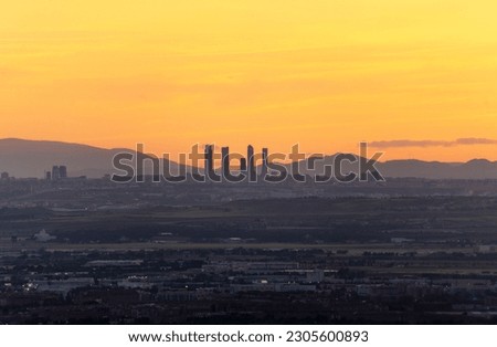 Spectacular orange sunset from Los Santos de la Humosa overlooking the valley of Henares and in the background the silhouette of the 5 towers of Madrid capital with the mountains nearby and the orange