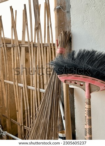 palm fiber broom and stick broom near the bamboo fence
