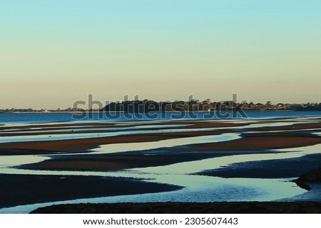 The wavy beach and water shoreline at dusk, with the ocean and horizon off in the distance. Natures beauty captured