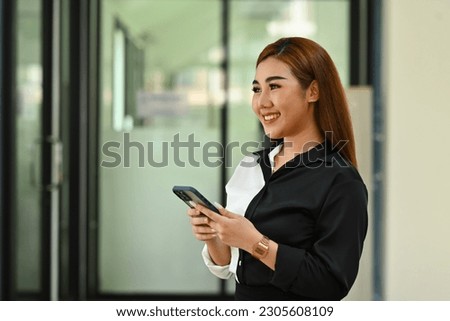 Attractive female investment advisor holding smartphones and looking out of the window, daydreaming, visualizing future