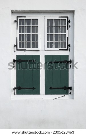 An old aesthetic window in the white wall of building