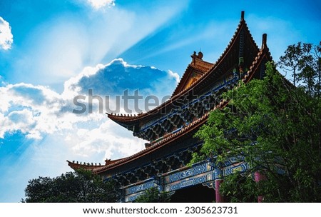 An ancient temple stands tall amidst lush trees and clouds, reflecting the deep history of religious beliefs in Chinese tradition. Royalty-Free Stock Photo #2305623731