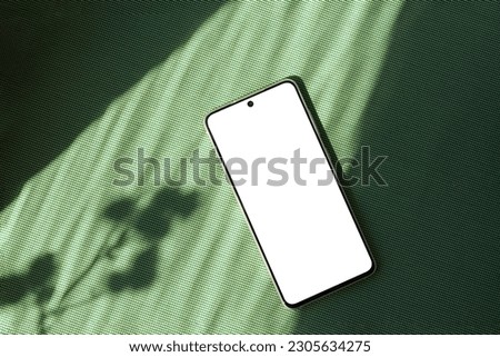 Minimalist summer business brand template, blank mobile phone screen mock up on a bright green textile background with aesthetic floral sun light shadow, copy space