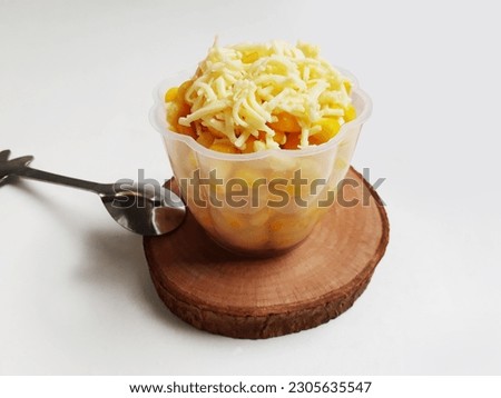 Jasuke is short for Jagung Susu Keju, which translates to corn, milk and cheese. A delicious Indonesian dessert,  made of steamed sweet corn mixed with milk and grated cheese. White background.