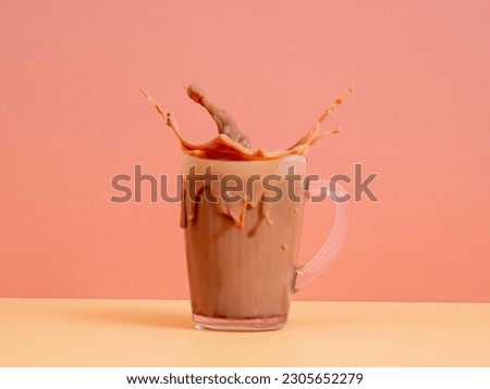 Splash of chocolate milk from a glass on a pink background. Cocoa in a glass. Splash of cocoa.
