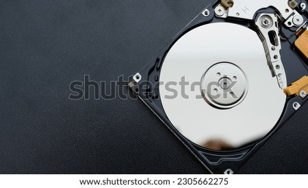 Disassembled open hard disk drive HDD of computer or laptop lies on dark matte surface. Сomputer hardware and equipment. Harddisk data storage.