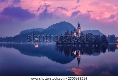 Church of Assumption in Lake Bled during sunset, with colorful sky and clouds. Stunning nature landscape. Scenic panoramic picture-postcard view of famous mountains lake in Slovenia.