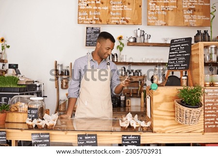 Black man, coffee shop and store phone of an entrepreneur with happiness from small business. Cafe, mobile and barista looking at online app with a smile at bakery and restaurant feeling happy Royalty-Free Stock Photo #2305703931