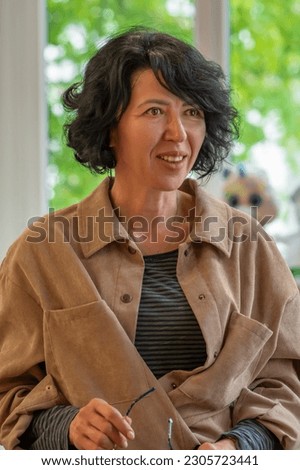 Portrait of a happy elderly woman with dark curly hair, 50-55 years old, vertical photo.