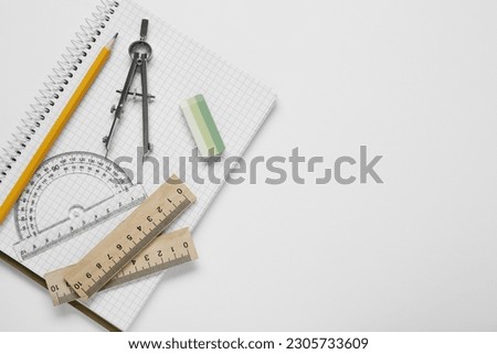 Different rulers, compass, pencil and notebook on white background, top view. Space for text Royalty-Free Stock Photo #2305733609