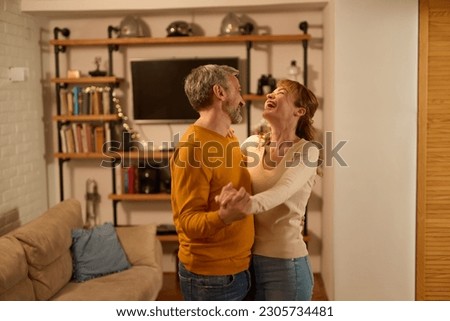 Mature couple dancing together in modern living room at home