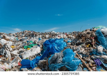 A pile of garbage in a landfill against a blue sky. Plastic scrap in landfill. Concept of ecology. Royalty-Free Stock Photo #2305759385
