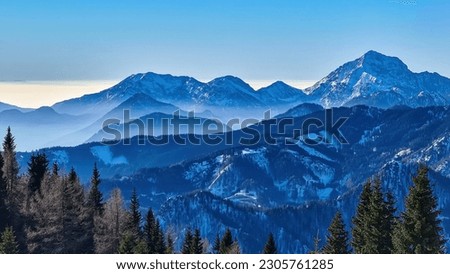 Panoramic view on snow capped mountain peaks of Karawanks in Carinthia, Austria. Julian Alps. Winter wonderland in the Austrian Alps, Europe. Ski tour, snow shoe hiking. Hochobir. Blue misty hills. Royalty-Free Stock Photo #2305761285