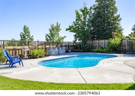 A pool in a residential backyard with blue chairs, green trees and a blue sky. Great for virtual staging