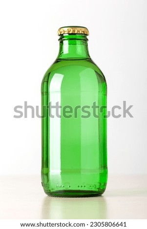 Green glass bottle of sparkling water with metal cap on a white background
