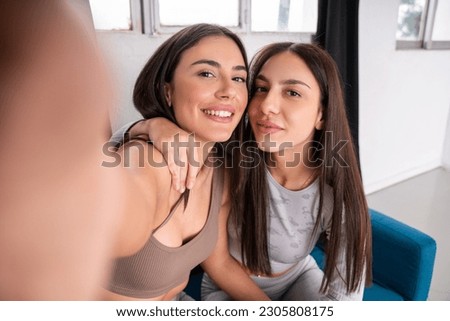 Two happy brunette sisters making selfie while bonding to each other