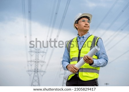 Electrical engineers holding blueprint looking confident with power line towers to project planning work producing electrical energy high voltage, energy concept. Royalty-Free Stock Photo #2305829417