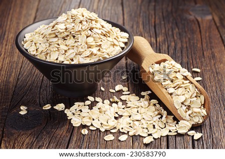 Oatmeal or oat flakes in bowl and scoop on dark wooden table  Royalty-Free Stock Photo #230583790