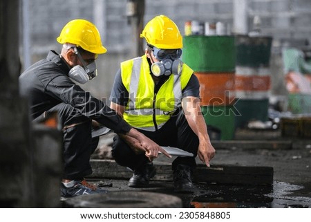 Two officers wearing gas masks inspected the area of a chemical leak in an industrial warehouse to assess the damage. Technicians wearing gas masks inspect and assess the recovery of toxic spills. Royalty-Free Stock Photo #2305848805