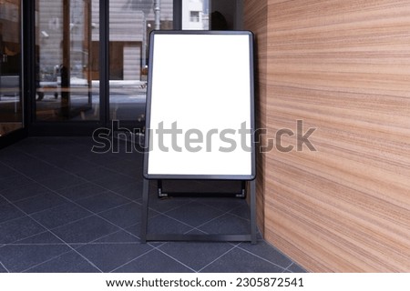 Blank white outdoor advertising stand sandwich board mock up template. Clear street signage board placed by an outdoor dinning area of a restaurant. Background texture of standee on street.