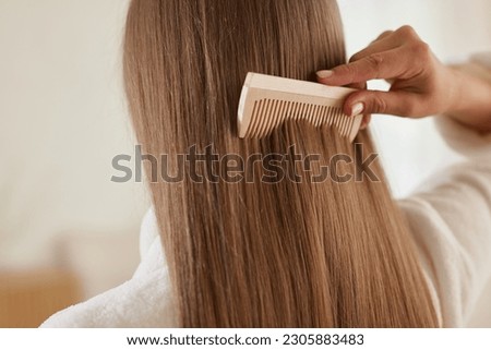 a young girl in a white coat takes care of her hair at home