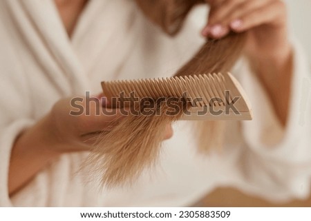 a young girl in a white coat takes care of her hair at home