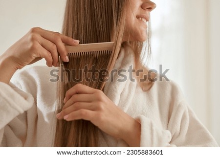 a young girl in a white coat takes care of her hair at home Royalty-Free Stock Photo #2305883601