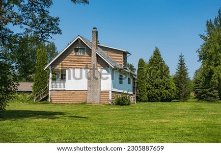 Beautiful house with a garden in a rural area. Traditional house with chimney on a sunny day with blue sky in the background. Travel photo, nobody