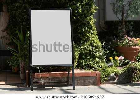 Blank white outdoor advertising stand  sandwich board mock up template. Clear street signage board placed by an outdoor dinning area of a restaurant. Background texture of standee on street.