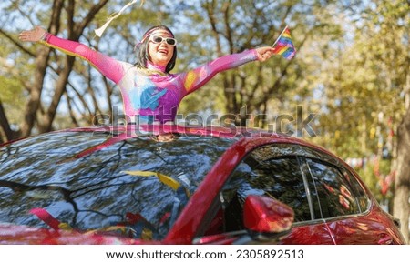 Happy Asian woman support LGBT pride parade in car. with Rainbow of LGBTQ or LGBTQIA