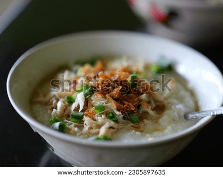 Bubur ayam Solo or Chicken Porridge, Indonesian traditional food consist of white rice porridge, shredded chicken, cakwe, fried soybean, crackers, leek and egg. Selective focus. Royalty-Free Stock Photo #2305897635