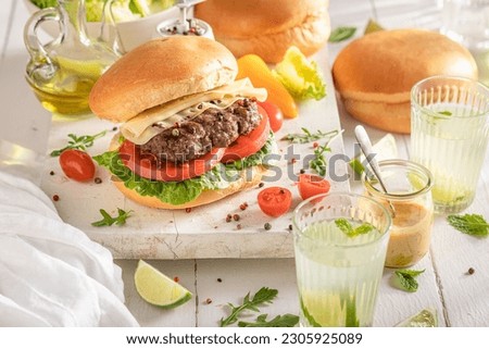Tasty grilled hamburger baked on a grilled. Grill cheeseburger with vegetables and bun.