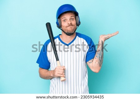 Baseball player with helmet and bat isolated on blue background having doubts while raising hands