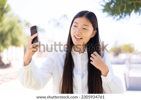 Pretty Chinese woman at outdoors making a selfie