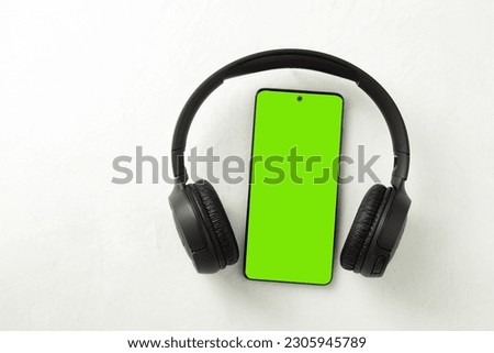 Mobile phone and headphones, close-up. Chromakey. Copy space. Close up of modern headphones on a portable phone holder