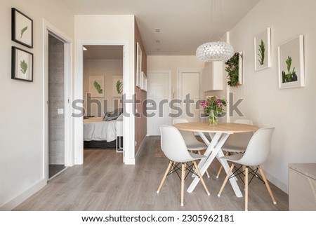 Stylish dining area in studio living room with table and chairs and decorative accessories overlooking the outdoor bathroom and bedroom. Concept of interior for a small apartmen Royalty-Free Stock Photo #2305962181