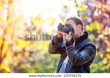 photographer with professional digital camera taking pictures in nature