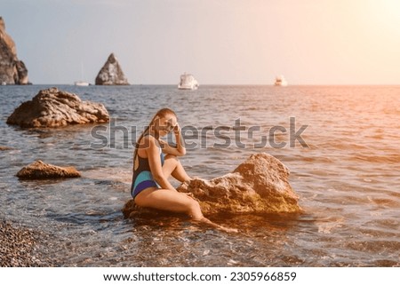 Woman travel sea. Happy tourist in blue swimwear takes a photo outdoors to capture memories. woman traveling and enjoying her surroundings on the beach, with volcanic mountains in the background.