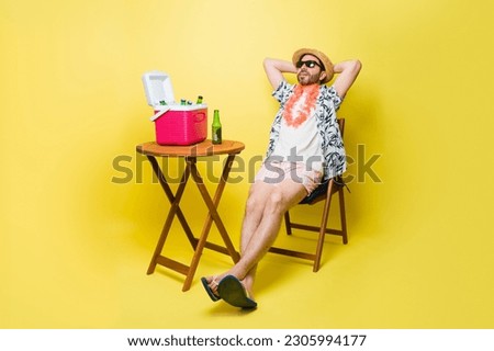 Relaxed man with shorts and sunglasses happy and relaxing with a beer in the summer at the beach in front of a yellow background