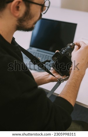 Close up of photographer putting back the sd card in his camera while sitting at the business table