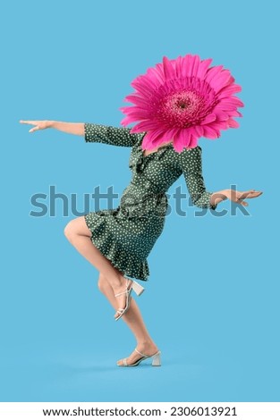 Dancing woman with gerbera flower instead of her head on blue background