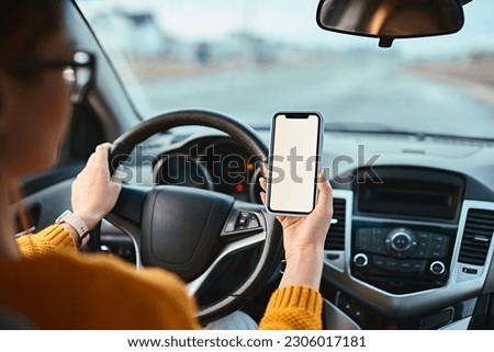 Woman driver using mobile phone screen blank mockup while driving distracted from the road.