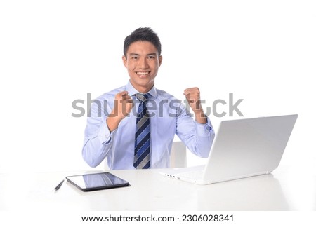portrait of young businessman sitting at desk using laptop.