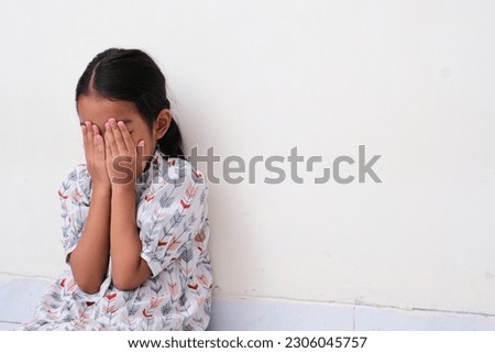 Asian little kid covering her face with hands showing sad expression Royalty-Free Stock Photo #2306045757